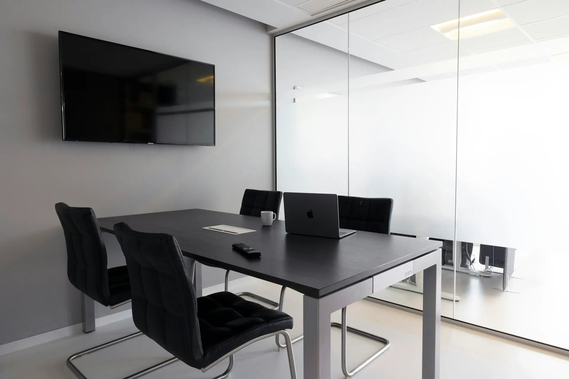 A meeting room fitted with office technology equipment and a display screen.